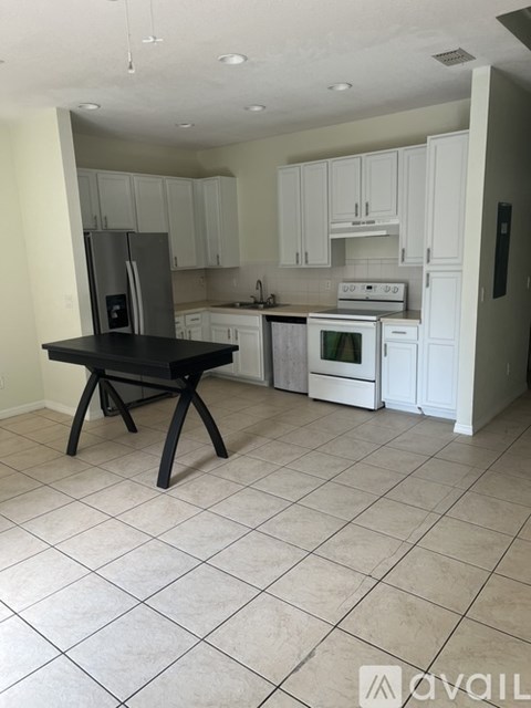 A kitchen with white cabinets and a black island.