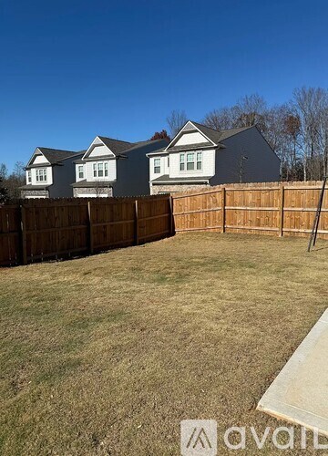 A backyard with a wooden fence and a house in the background.
