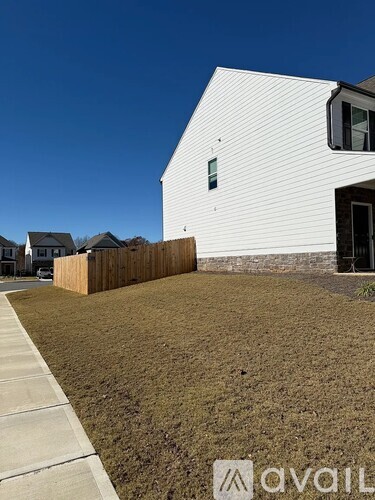 A modern house with a white exterior and a wooden fence in front.