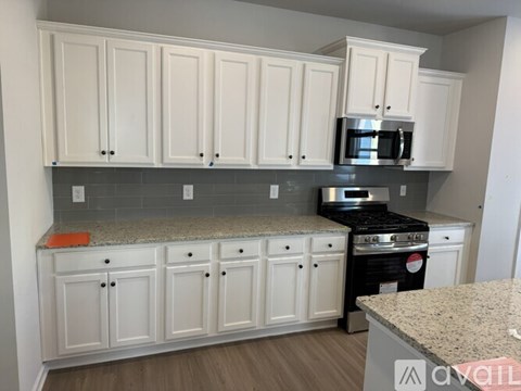 A kitchen with white cabinets and a granite countertop.