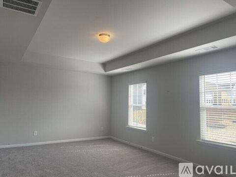 A spacious room with a carpeted floor and a window with blinds.