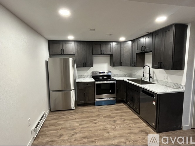 A kitchen with black cabinets and a stainless steel refrigerator.