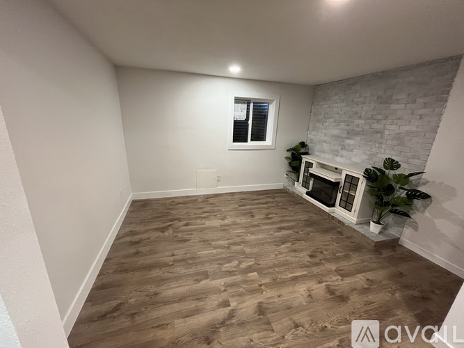 A room with wooden flooring and a fireplace.