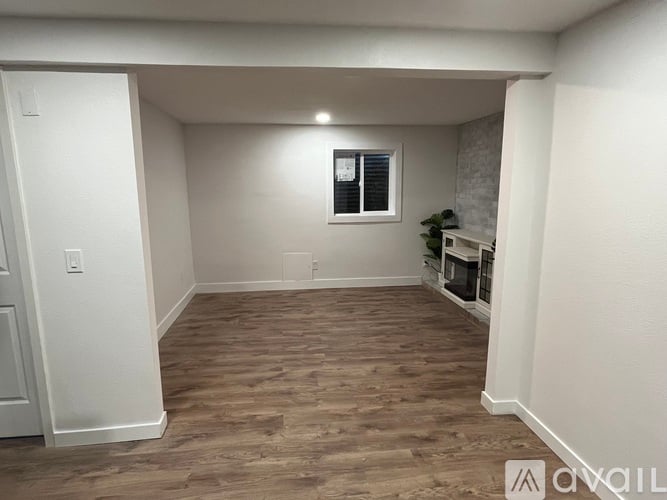 A room with wooden flooring and a window with blinds.