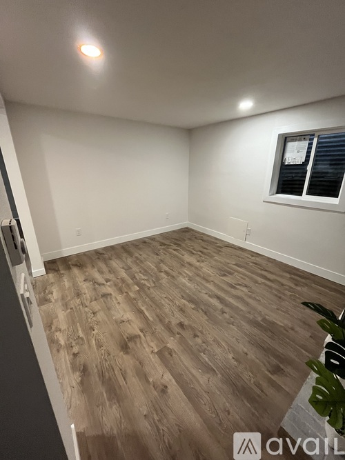 A room with wooden flooring and a window with blinds.