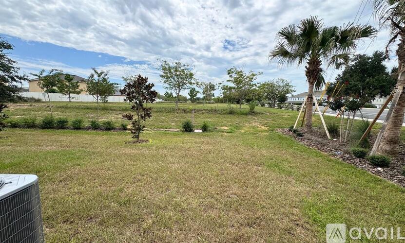 A grassy field with a few trees and a fence in the foreground.