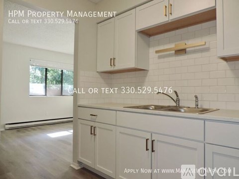 A kitchen with white cabinets and a sink is shown with an advertisement for HPM Property Management.