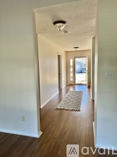A hallway with a rug on the floor and a door at the end.