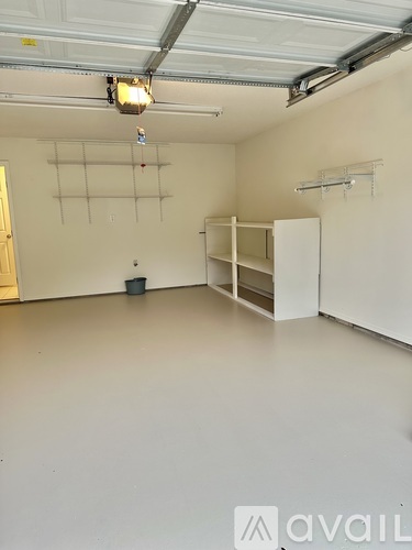 A large empty room with a white floor and a white ceiling with a light hanging from it.