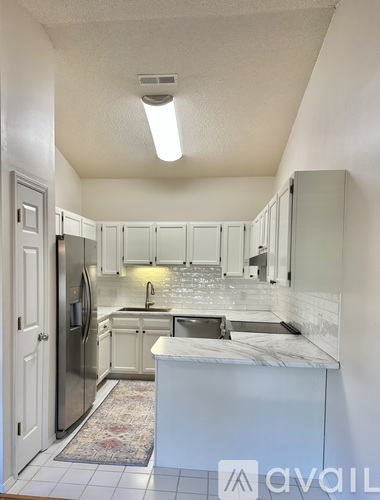A kitchen with white cabinets and a marble countertop.