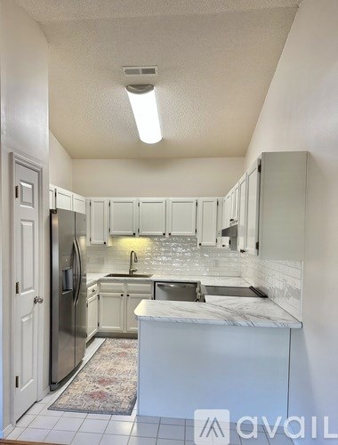 A kitchen with white cabinets and a marble countertop.