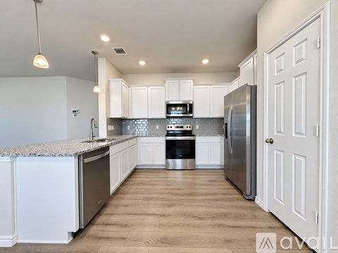 A modern kitchen with white cabinets and stainless steel appliances.