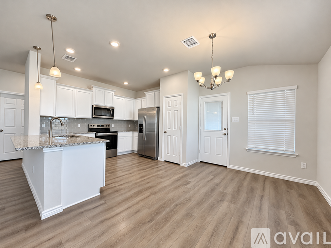 A spacious kitchen with white cabinets and a wooden floor.