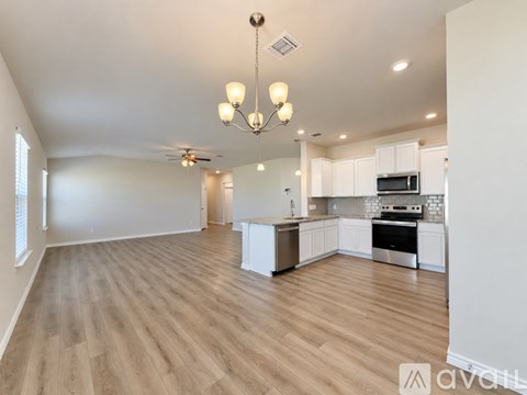 A spacious kitchen and living room with wooden flooring and white walls.