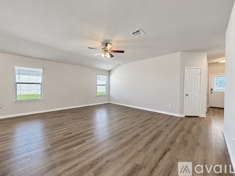 A spacious room with wooden flooring and a ceiling fan.