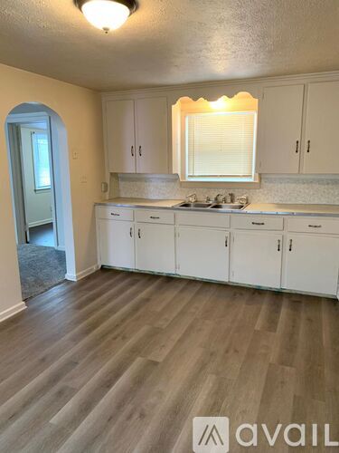 A kitchen with white cabinets and a wooden floor.