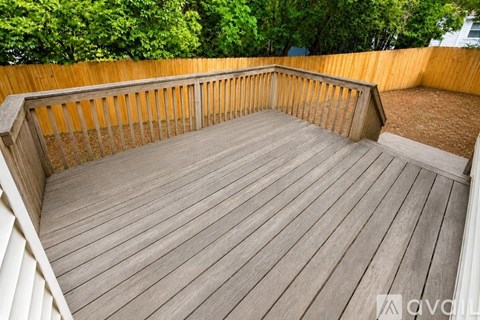 A wooden deck with a railing and trees in the background.