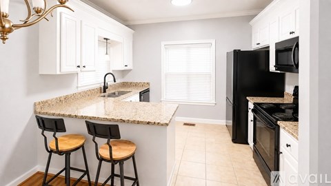 A kitchen with black appliances and white cabinets.