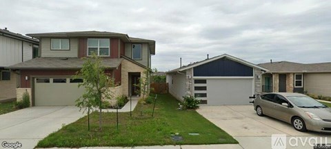 A two-story house with a garage and a car parked in front.