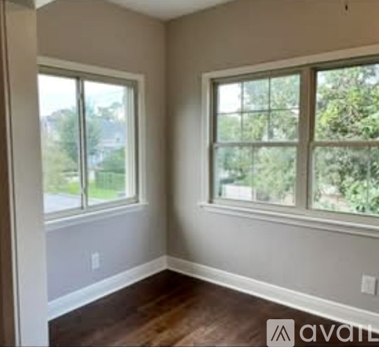 A room with two windows and wooden floors.