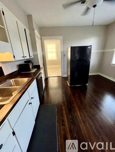 A kitchen with white cabinets and a black fridge.