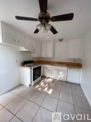 A kitchen with white cabinets and a fan on the ceiling.