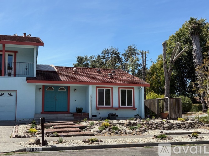 A white house with a red roof and a blue door.