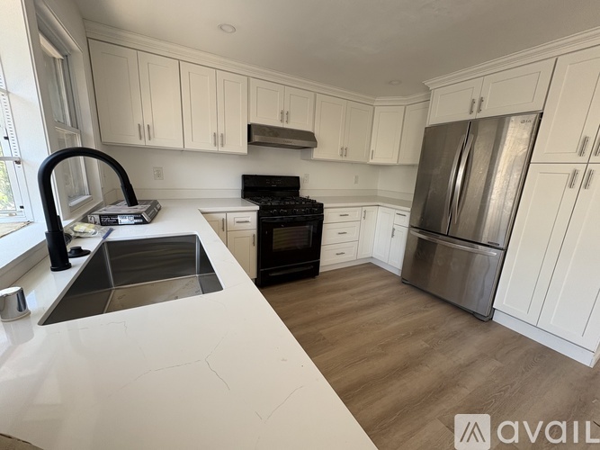 A kitchen with white cabinets and a wooden floor.