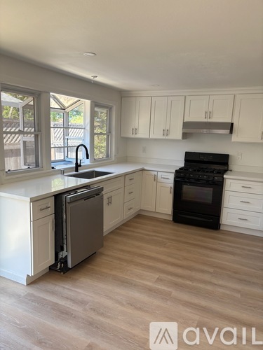 A kitchen with white cabinets and a black stove top oven.