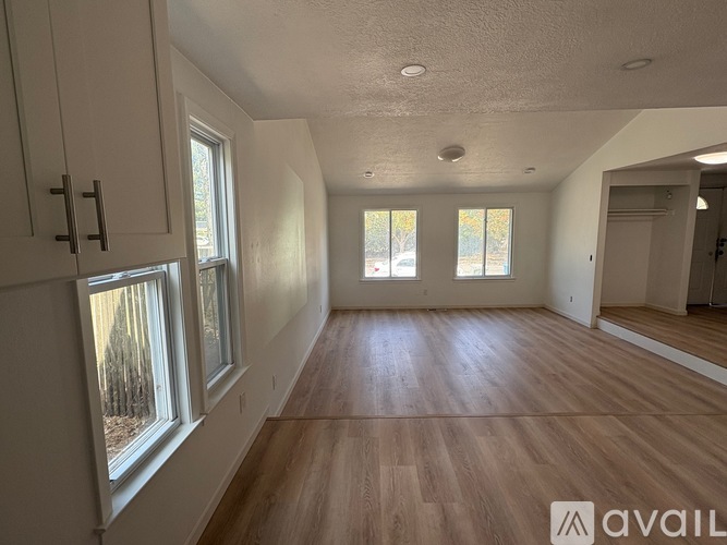 A spacious room with wooden floors and white walls.