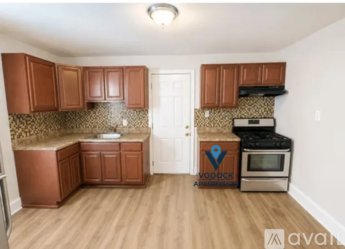 A kitchen with wooden cabinets and a Vodock Apartments logo.