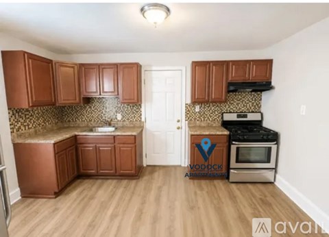 A kitchen with wooden cabinets and a Vodock Apartments logo.