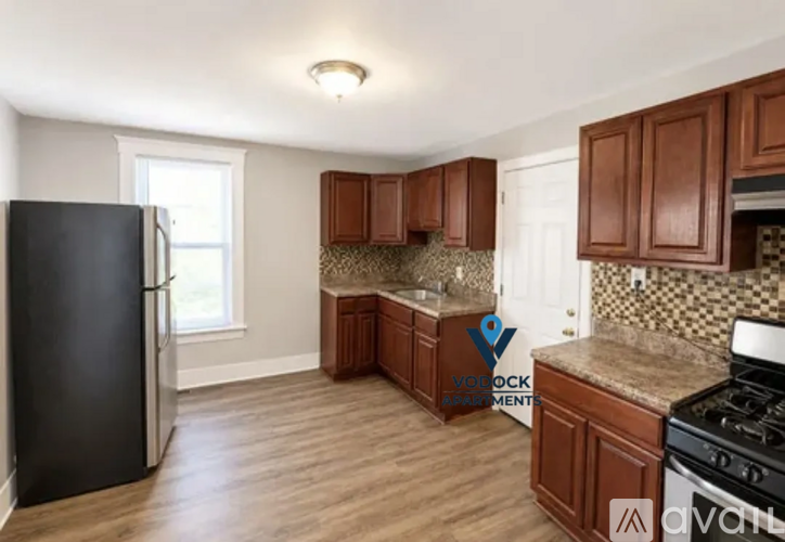 A kitchen with wooden cabinets and a black refrigerator.