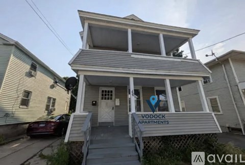 A two-story building with a balcony and a sign that says "YODOCK APARTMENTS" is available for rent.