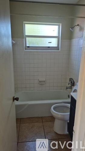 A bathroom with a toilet, tub, and window.