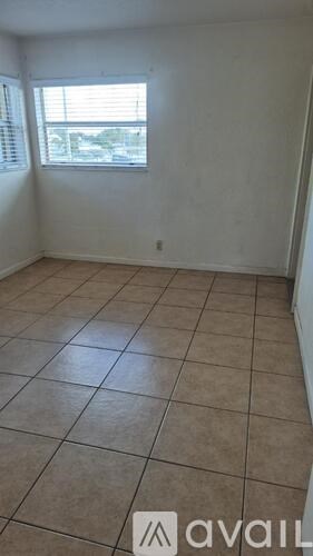 A room with tiled flooring and a window with blinds.