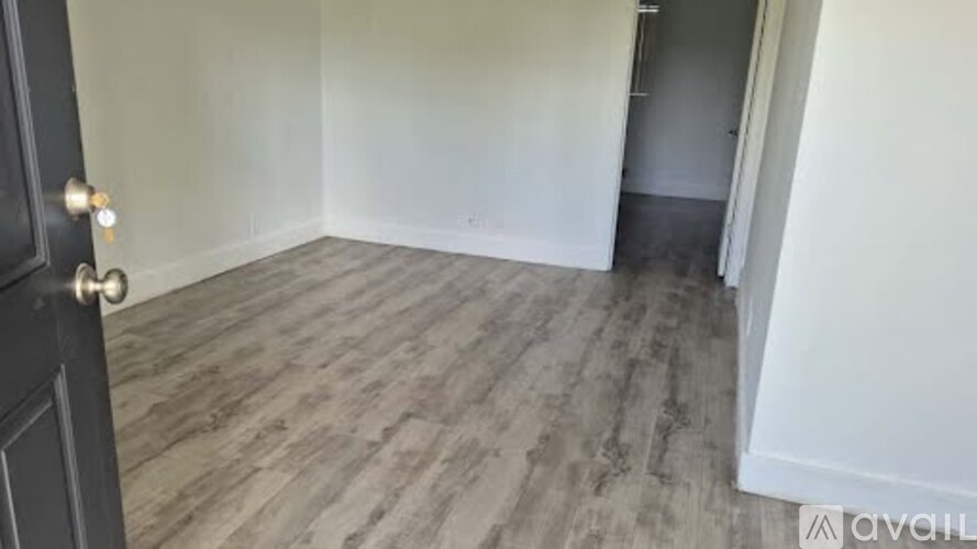 A room with a wooden floor and a door on the left.