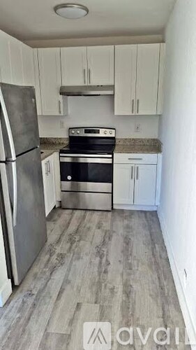 A kitchen with a refrigerator, oven, and cabinets.