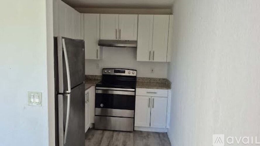 A kitchen with a refrigerator, oven, and cabinets.