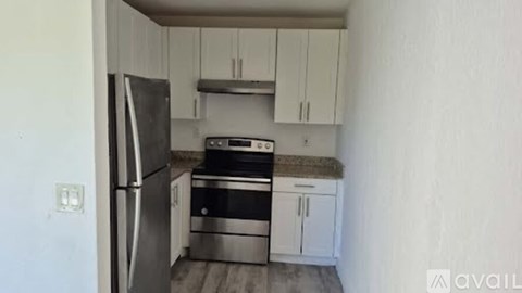 A kitchen with a refrigerator, oven, and cabinets.