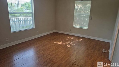 A room with wooden flooring and a window with blinds.