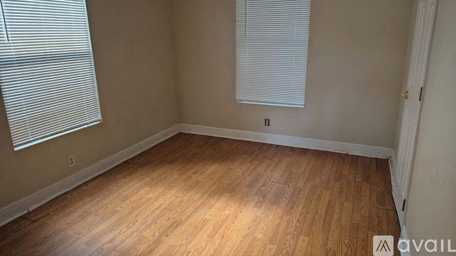 A room with wooden flooring and a window with blinds.
