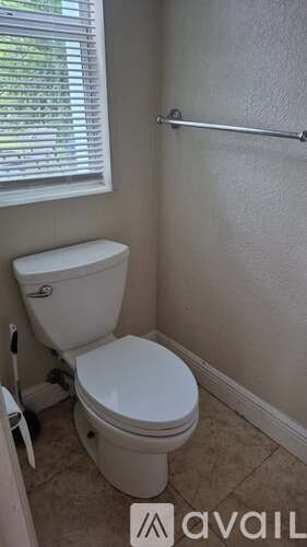 A white toilet in a small bathroom with a window.