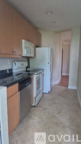 A kitchen with a white fridge and black countertops.