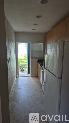 A kitchen with a refrigerator and a doorway leading to a balcony.