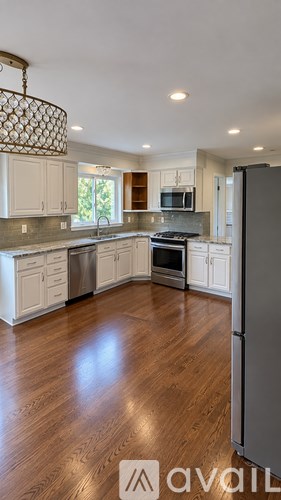 A kitchen with wooden floors and a refrigerator on the right side.