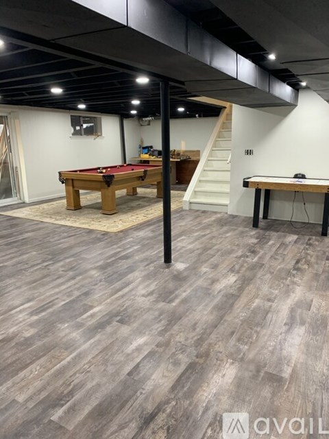A room with a pool table and a staircase in the background.