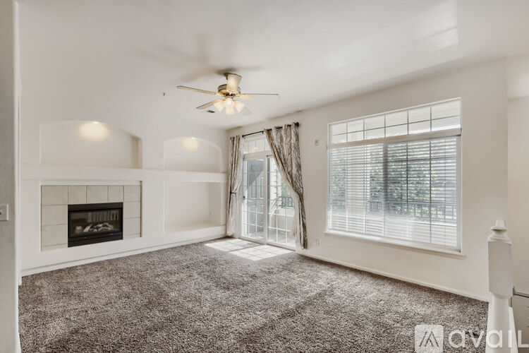 A spacious living room with a fireplace and a ceiling fan.