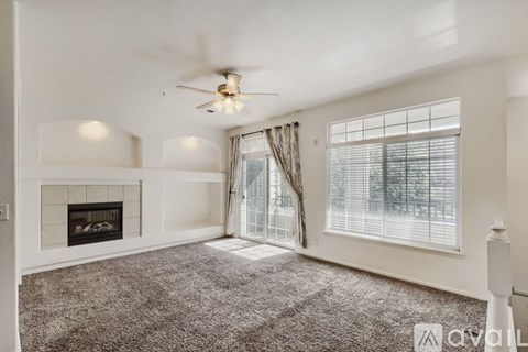 A spacious living room with a fireplace and a ceiling fan.