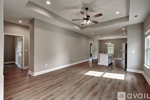 A spacious room with a ceiling fan and wooden flooring.